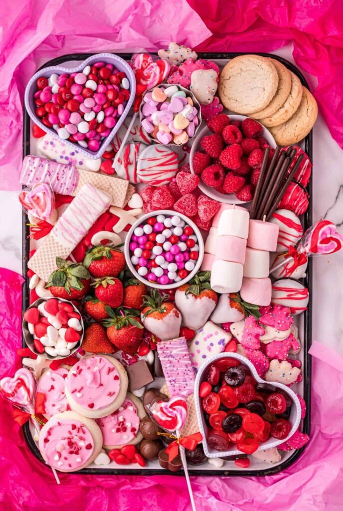 Pink grazing board with cookies, candy and fruit